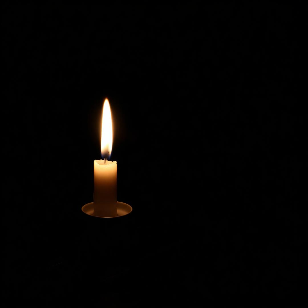 Chama de vela solitária sobre madeira escura, brilho suave e contemplativo